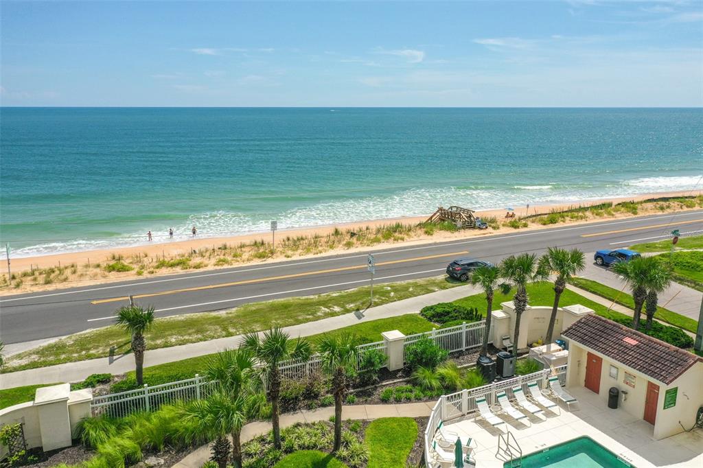 An elevated view of a beach, a coastal road, and a swimming pool area below — 300 MARINA BAY DRIVE UNIT 106, FLAGLER BEACH, FL