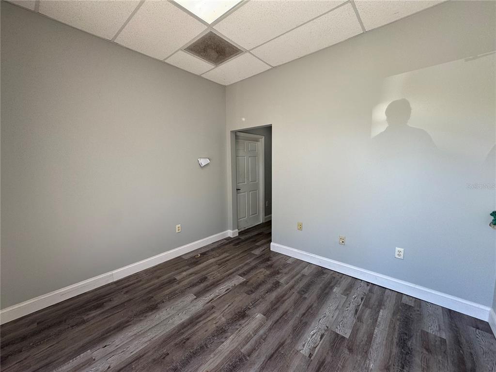 An empty room with gray walls, wood-look flooring, and a drop ceiling — 1408 HAMLIN AVENUE UNIT D, ST CLOUD, FL