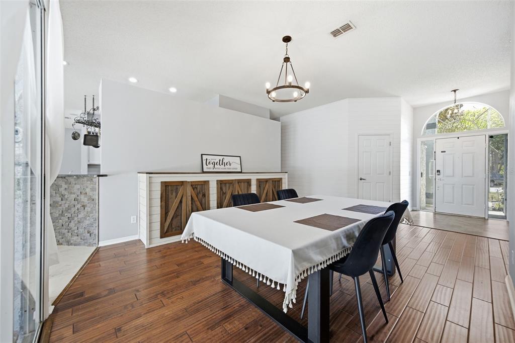 A dining room features a farmhouse-style sideboard, a chandelier, and a table with black chairs — 28707 RALEIGH PLACE, WESLEY CHAPEL, FL