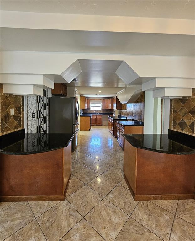 A kitchen features wood cabinets, black granite countertops, and diagonal tile flooring — 3709 WESTGATE ROAD, ORLANDO, FL