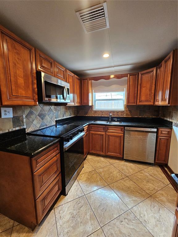 A kitchen features wood cabinets, black granite countertops, stainless steel appliances, and tiled flooring — 3709 WESTGATE ROAD, ORLANDO, FL