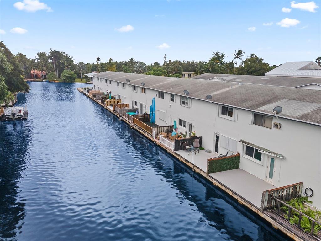 An aerial view shows a row of waterfront townhomes with private decks along a canal — 1818 E OAKLAND PARK BOULEVARD UNIT 83, OAKLAND PARK, FL