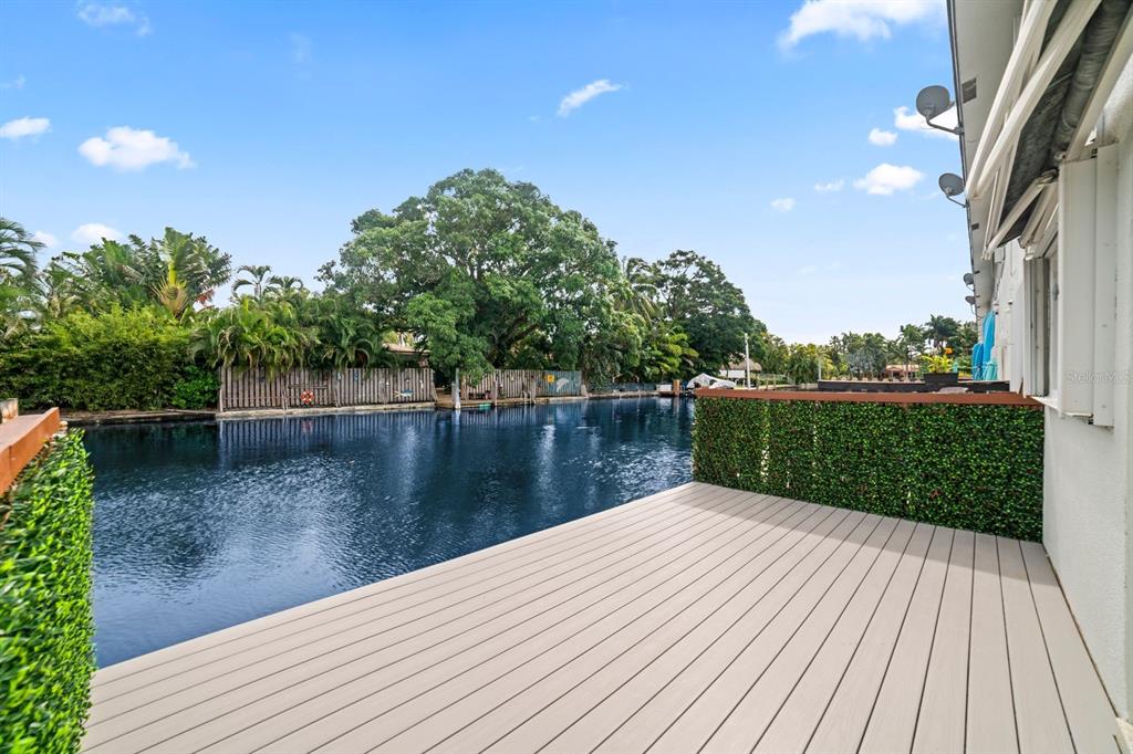 A wooden deck overlooks a canal lined with trees and a wooden fence — 1818 E OAKLAND PARK BOULEVARD UNIT 83, OAKLAND PARK, FL