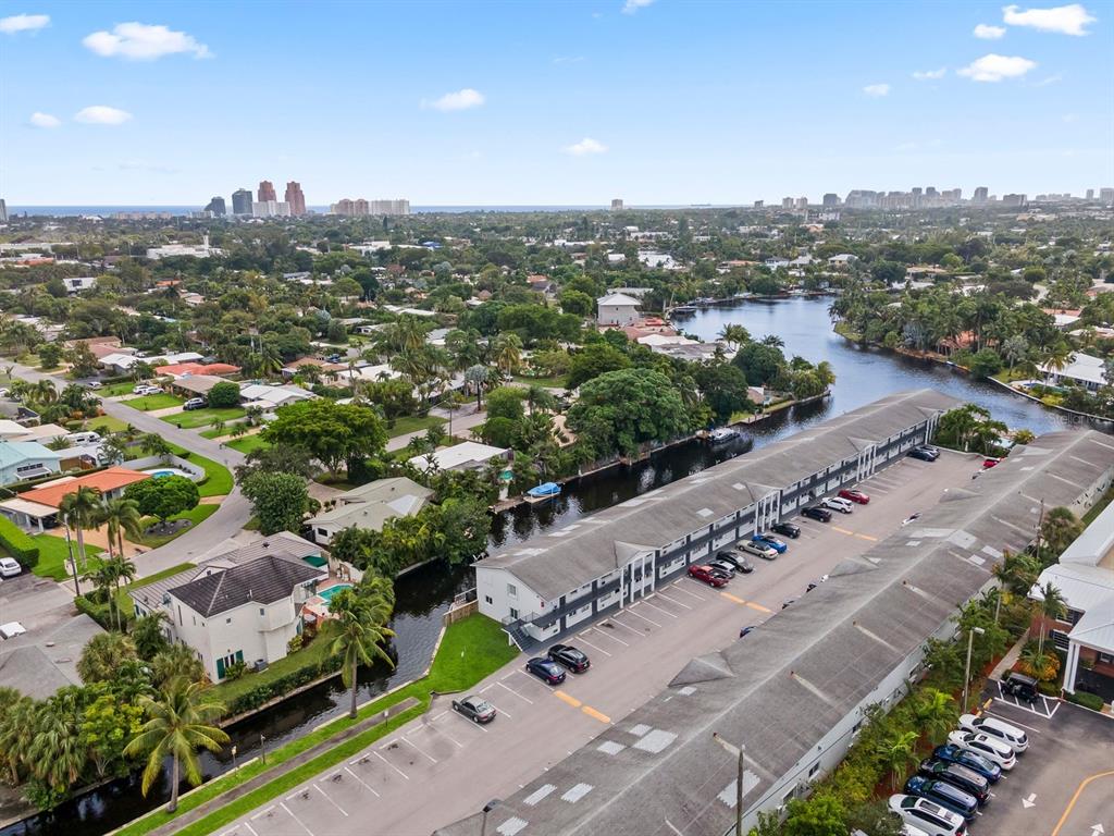 An aerial view shows a long apartment building with parking lots beside a narrow canal — 1818 E OAKLAND PARK BOULEVARD UNIT 83, OAKLAND PARK, FL