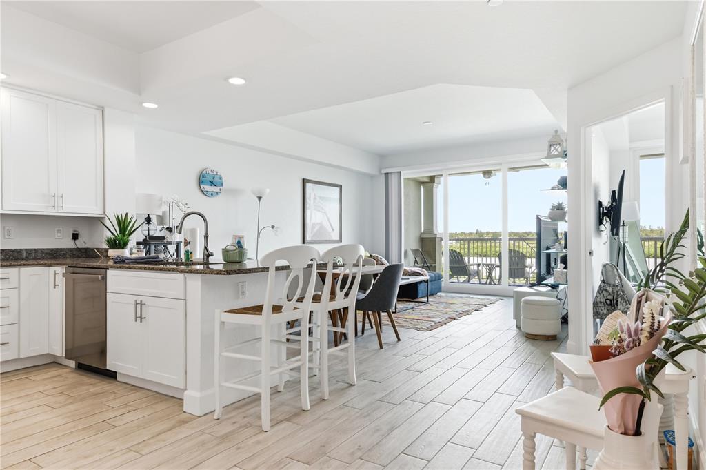 An open-concept kitchen and living area features white cabinetry, granite countertops, and a balcony view — 19519 GULF BOULEVARD UNIT 403, INDIAN SHORES, FL