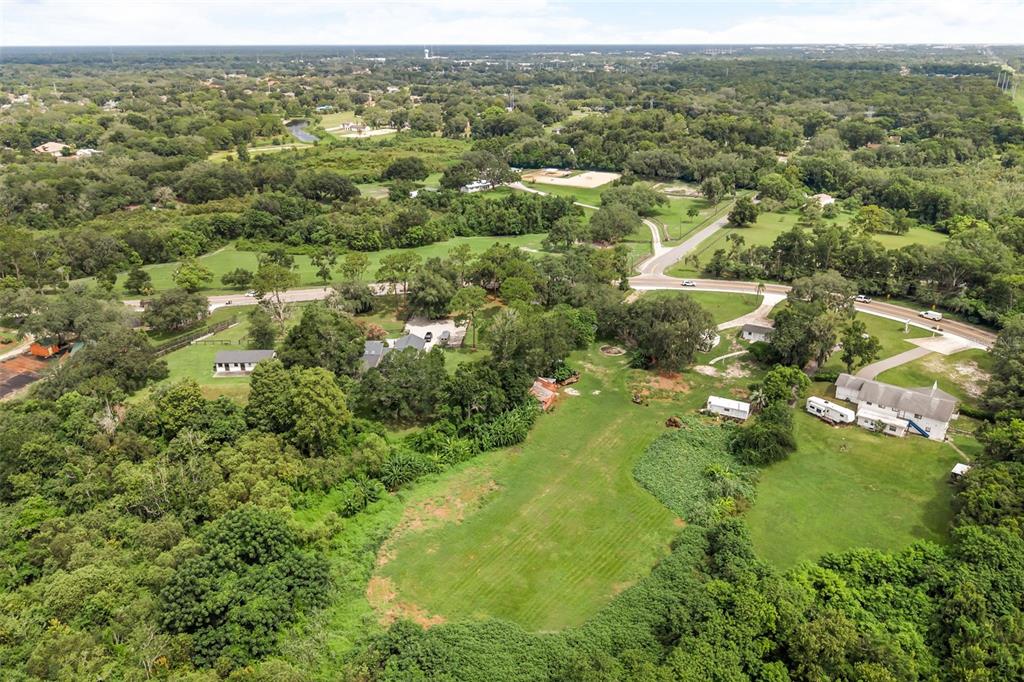 An aerial view shows a large, grassy property with several buildings, trees, and paved roads — 250 LONGWOOD HILLS ROAD, LONGWOOD, FL