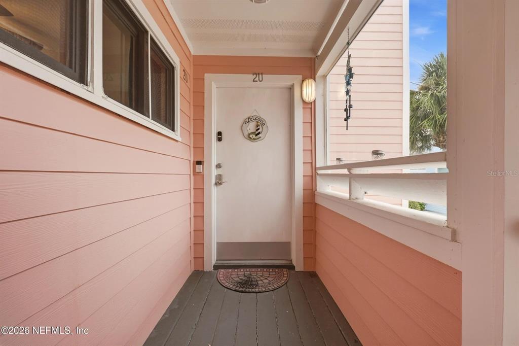 A covered porch features peach-colored siding, a white front door, and a dark wooden floor — 6300 A1A S UNIT A92U, ST AUGUSTINE, FL