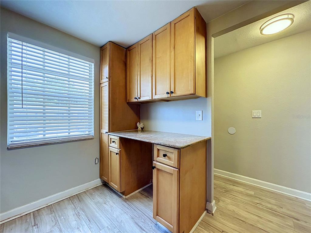 A built-in wooden desk and cabinetry are situated next to a window in a room — 4227 SHELDON PLACE UNIT -, NEW PORT RICHEY, FL
