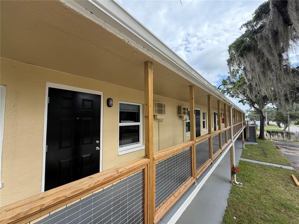 An exterior view of a motel-style building with a wooden walkway and black doors — 419 GRAPEFRUIT AVENUE UNIT 8B, SEBRING, FL