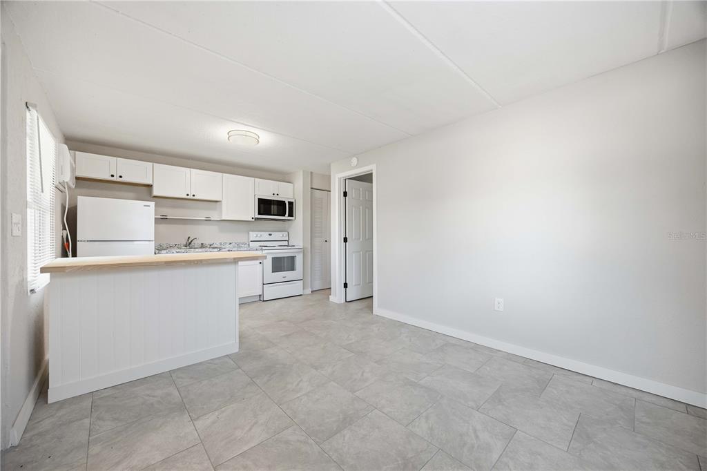 A kitchen with white cabinets and appliances features a breakfast bar and tile flooring — 419 GRAPEFRUIT AVENUE UNIT 8B, SEBRING, FL