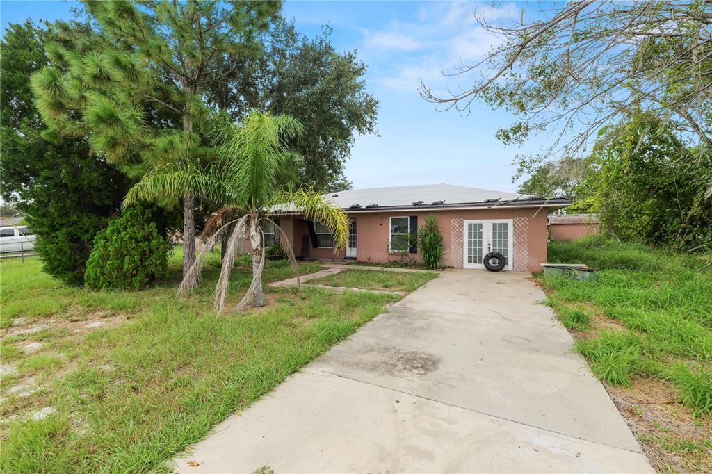 A single-story house with a concrete driveway, a palm tree, and a metal roof — 136 MADERA DRIVE, WINTER HAVEN, FL