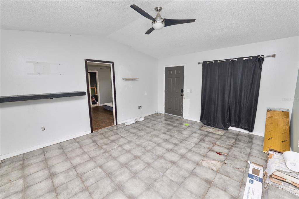 An empty room features gray tile flooring, a ceiling fan, and a dark doorway — 136 MADERA DRIVE, WINTER HAVEN, FL