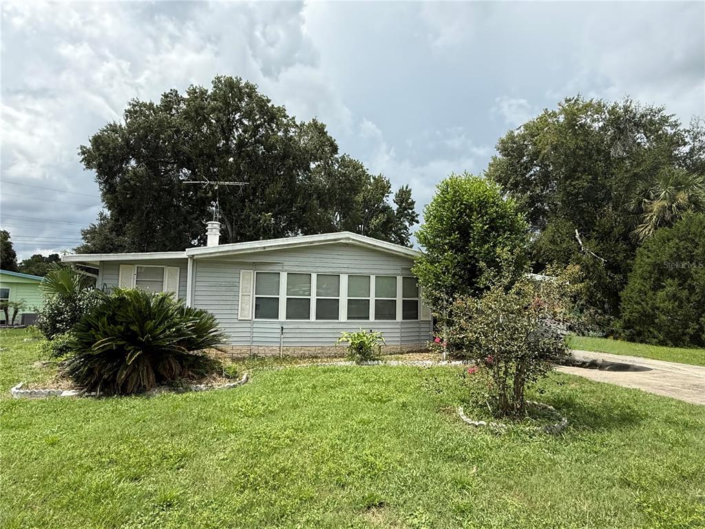 A light gray single-story house with a large front window sits on a grassy lot — 4 GROVE COURT, WILDWOOD, FL