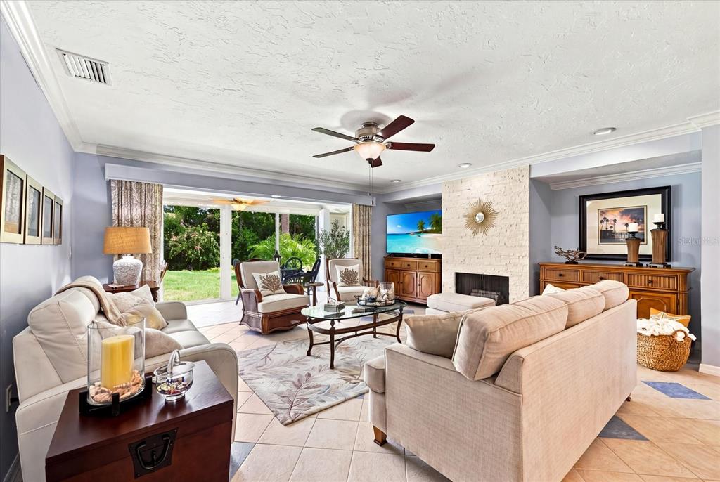 A living room features light-colored sofas, a stone fireplace, and sliding glass doors to a patio — 3252 RINGWOOD MEADOW UNIT 81, SARASOTA, FL