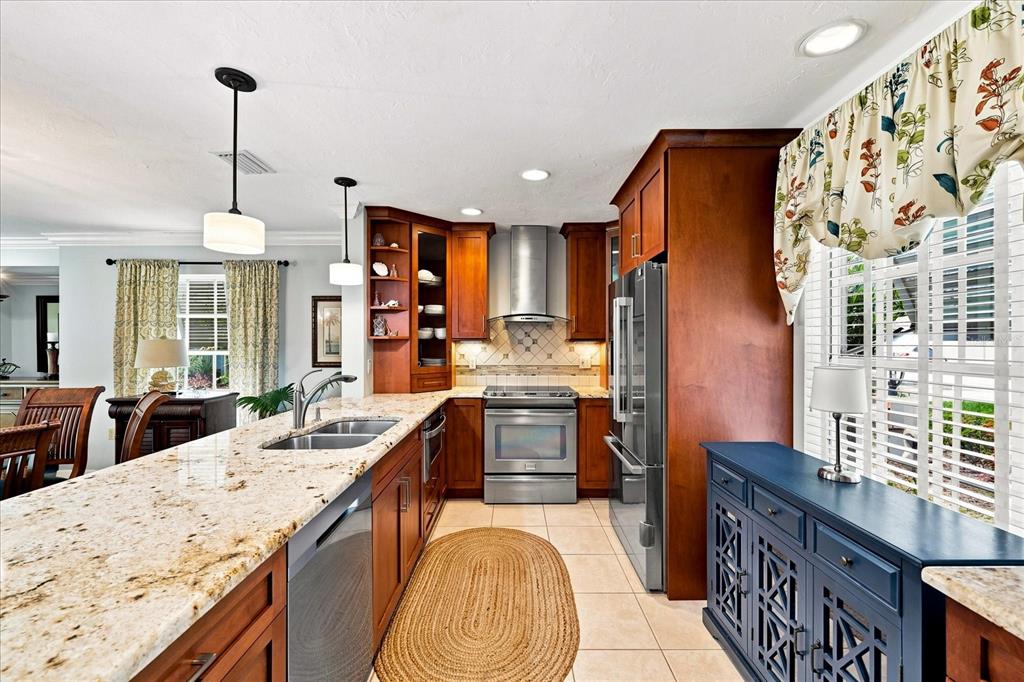 A kitchen features wood cabinets, granite countertops, stainless steel appliances, and a blue sideboard — 3252 RINGWOOD MEADOW UNIT 81, SARASOTA, FL
