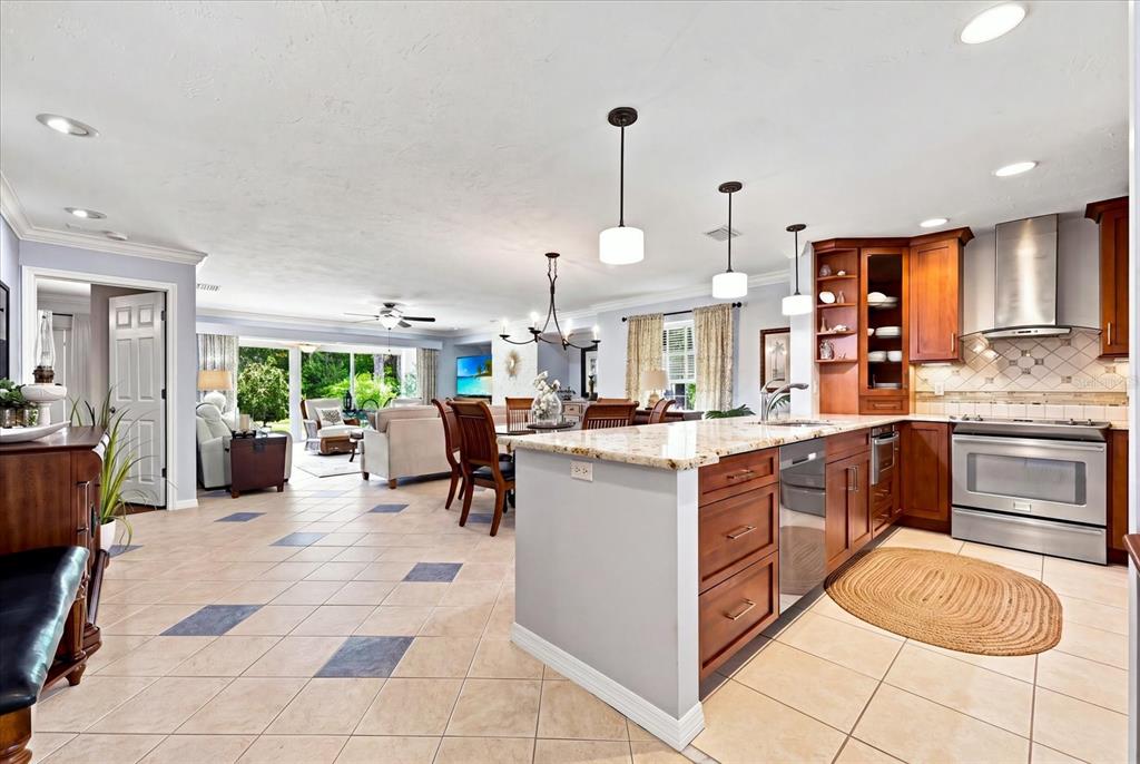 A kitchen with wood cabinets and a granite island opens into a living room area — 3252 RINGWOOD MEADOW UNIT 81, SARASOTA, FL