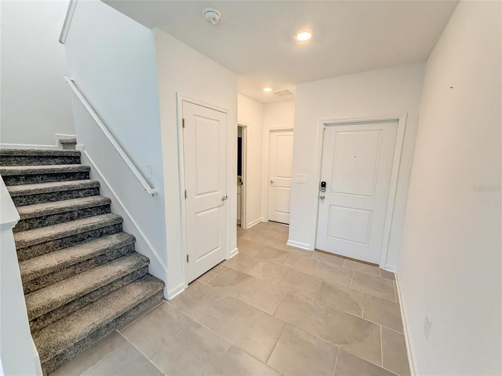 An entryway features gray tile flooring, a carpeted staircase, and three white interior doors — 832 TIMBERLAND DRIVE, EAGLE LAKE, FL