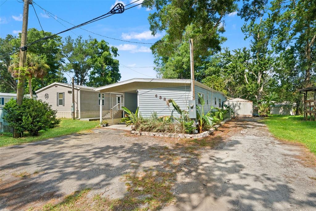 A light blue mobile home features a covered carport and a gravel driveway — 6380 RICHARD DRIVE, WEEKI WACHEE, FL