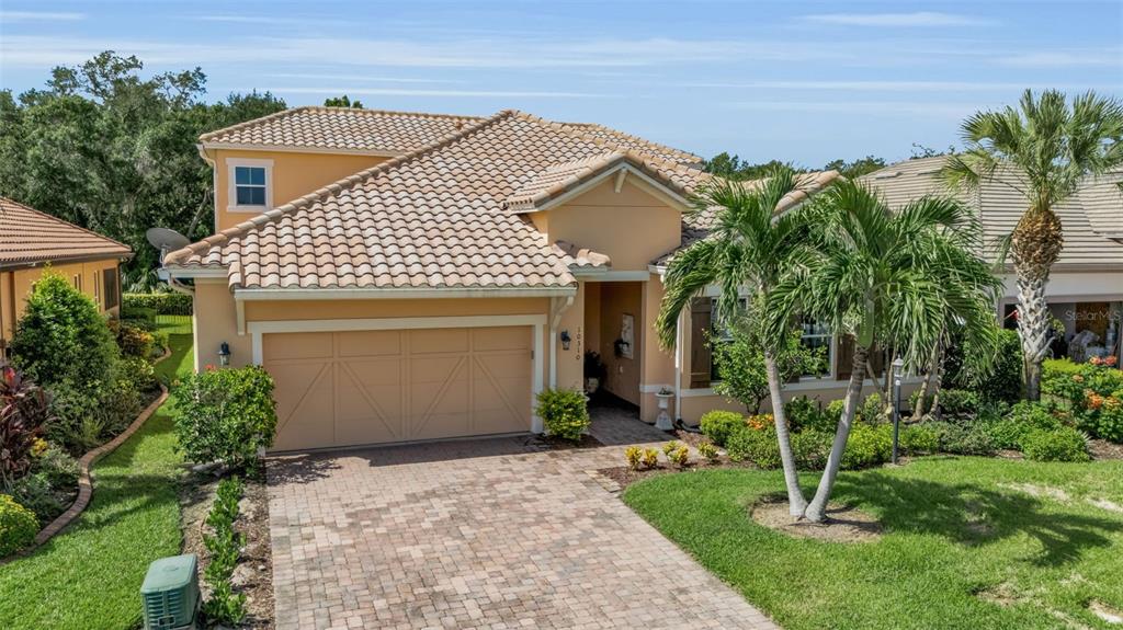 An exterior view of a single-story house with a tan stucco facade and tiled roof — 10310 EASTWOOD DRIVE, BRADENTON, FL