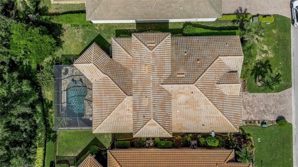 An aerial view shows a house with a tiled roof, a screened-in pool, and landscaping — 10310 EASTWOOD DRIVE, BRADENTON, FL