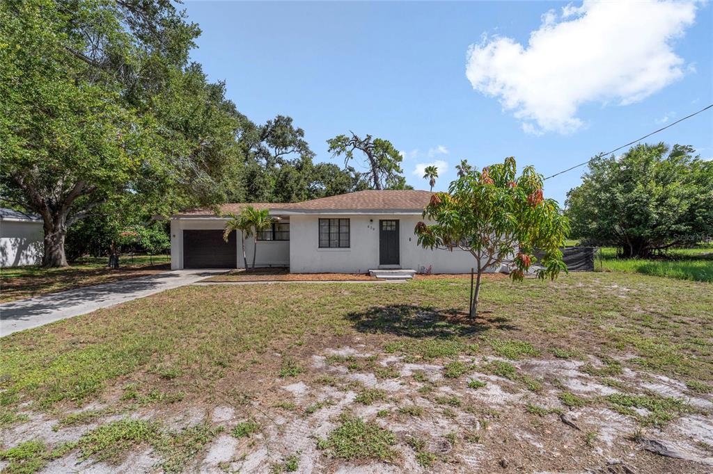A single-story white house with a dark garage door and a front yard — 839 42ND STREET, SARASOTA, FL