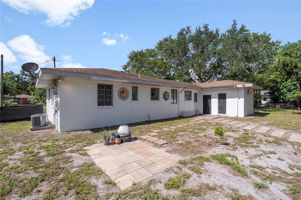 The exterior of a white, single-story house features a small patio and a sandy yard — 839 42ND STREET, SARASOTA, FL