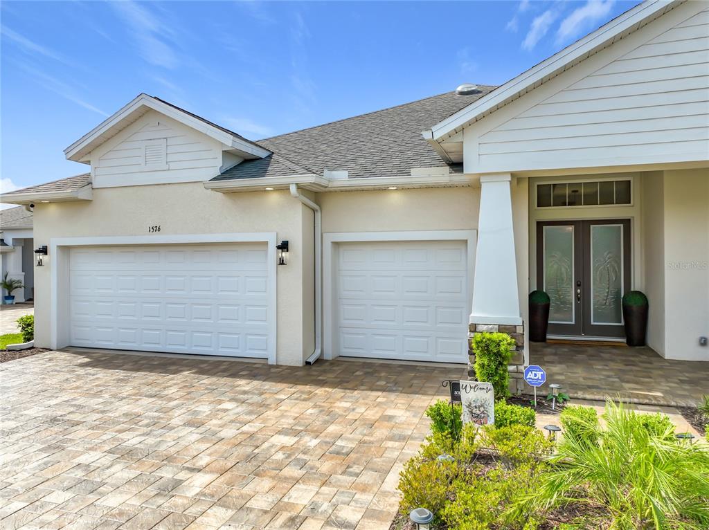 An aerial view shows three suburban houses with paved driveways facing a pond and neighborhood — 1576 LAKE RESERVE DRIVE, DELAND, FL