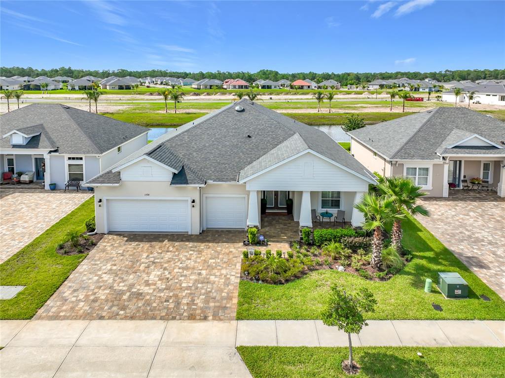 A beige house exterior features a three-car garage, a paved driveway, and a front entrance — 1576 LAKE RESERVE DRIVE, DELAND, FL