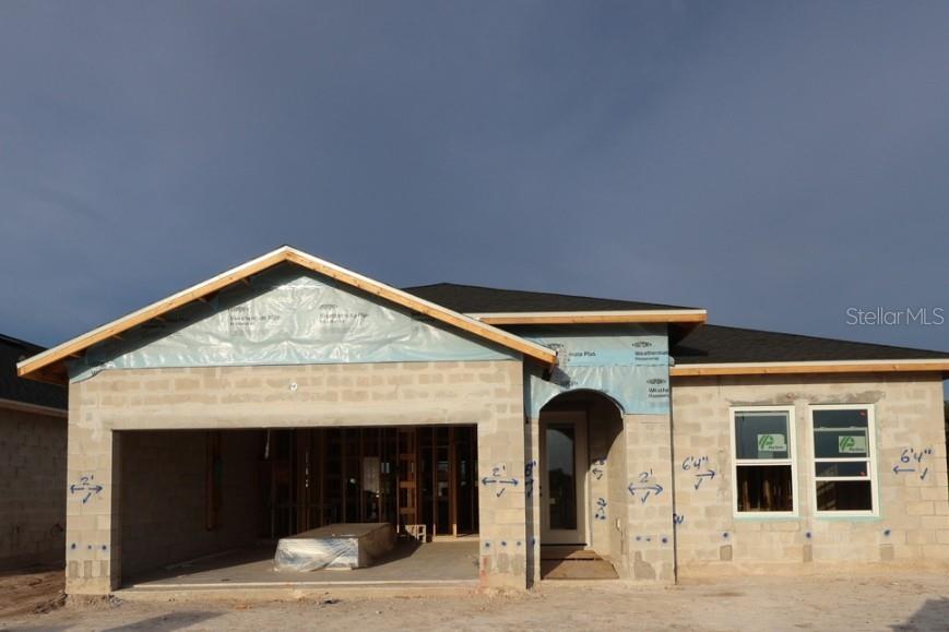 A single-story house under construction with a concrete block exterior, garage, and shingled roof — 5665 COOPERS HAWK COURT, ST CLOUD, FL