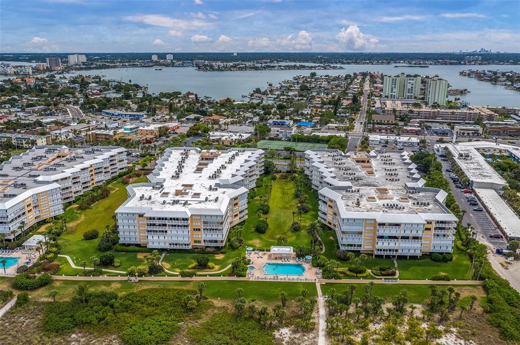 An aerial view shows two large apartment buildings with a central pool and green space — 6500 SUNSET WAY UNIT 116, ST PETE BEACH, FL