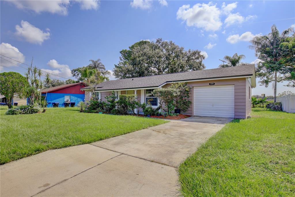 A single-story house with a tan exterior, a white garage door, and a concrete driveway — 2319 CONTINENTAL BOULEVARD, ORLANDO, FL
