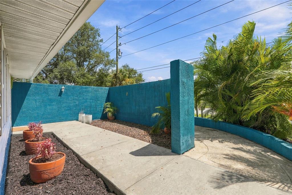 A blue and white house exterior features a concrete walkway, potted plants, and a door — 4720 WELCH CAUSEWAY, ST PETERSBURG, FL