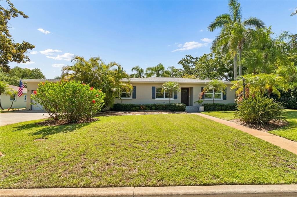 A single-story house with a two-car garage, a concrete driveway, and lush tropical landscaping — 1743 EAGLES NEST DRIVE, BELLEAIR, FL