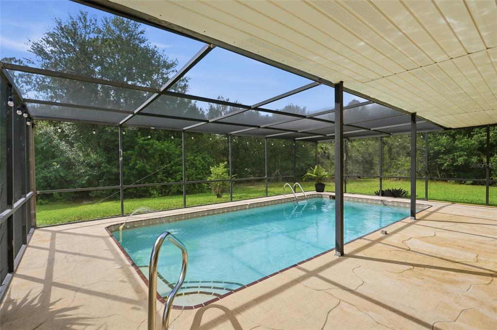 A screened-in swimming pool with a concrete deck sits under a covered patio roof — 28265 MORNINGSIDE DRIVE, PUNTA GORDA, FL