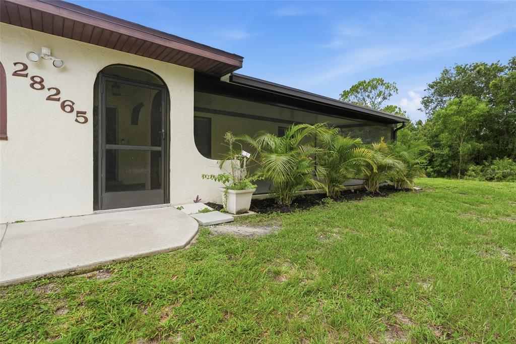 A house exterior features a screened-in porch, a front door, and palm trees in front — 28265 MORNINGSIDE DRIVE, PUNTA GORDA, FL