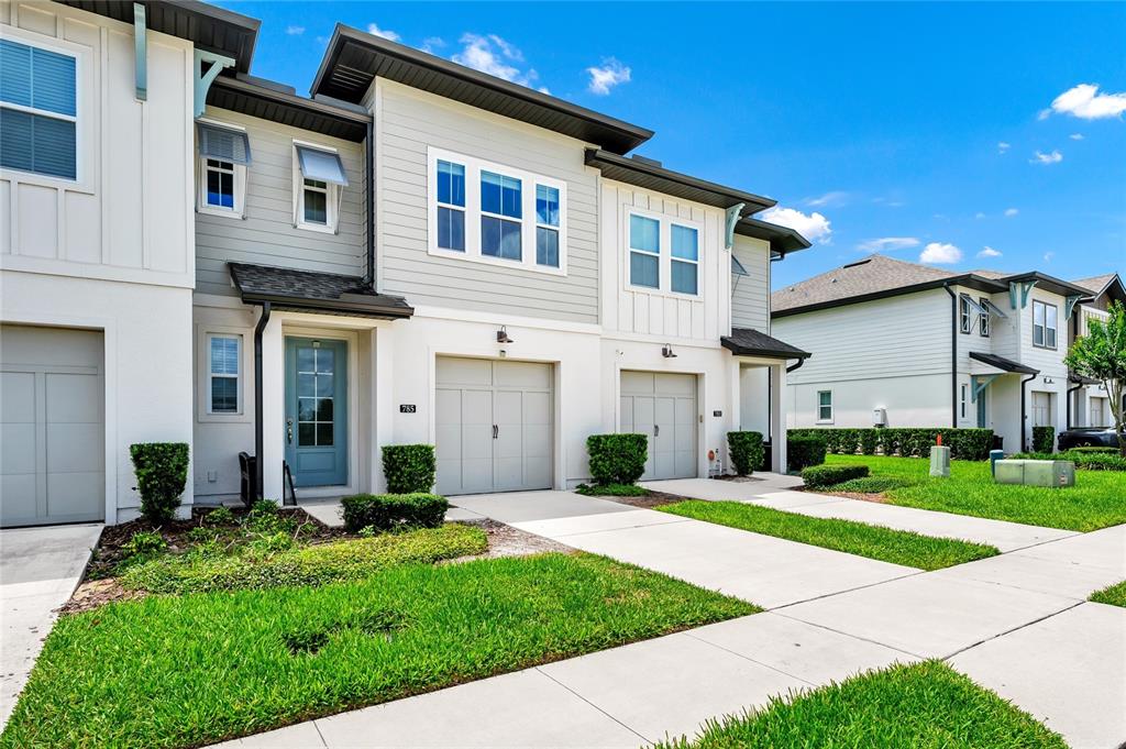 A two-story townhouse exterior features a light blue front door and a single-car garage — 785 BENOI DRIVE, DAVENPORT, FL
