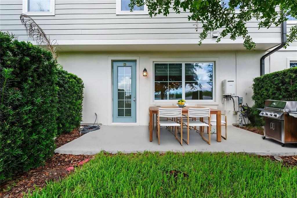 A concrete patio features a wooden dining set and a grill against a house exterior — 785 BENOI DRIVE, DAVENPORT, FL