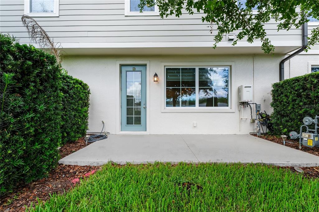 A concrete patio sits outside a light blue door and a window on a house — 785 BENOI DRIVE, DAVENPORT, FL