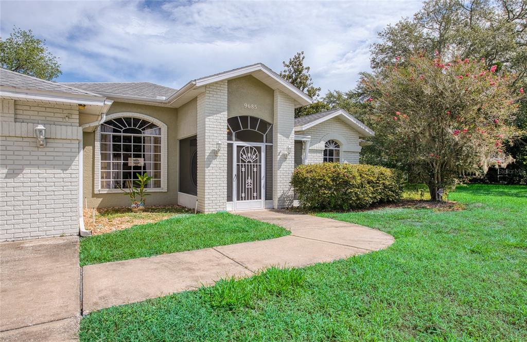 A single-story house with a white brick facade, arched windows, and a screened front entryway — 9685 SOUTHERN BELLE DRIVE, WEEKI WACHEE, FL