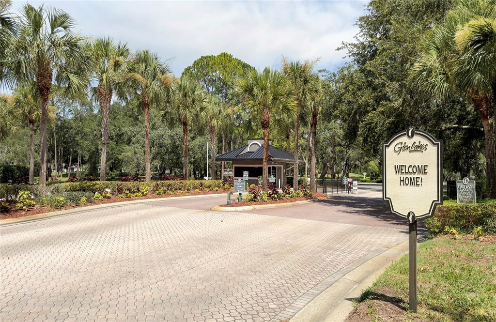 A paved entrance with a guardhouse, palm trees, and a Glenlakes welcome sign — 9685 SOUTHERN BELLE DRIVE, WEEKI WACHEE, FL