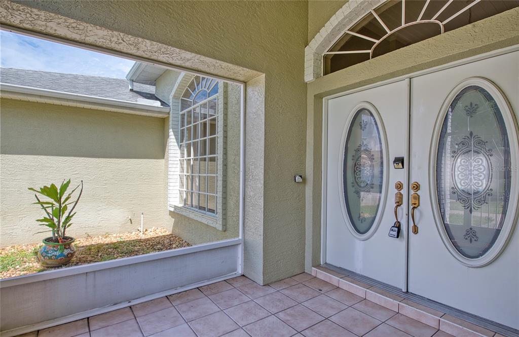 A tiled entryway features double white doors with oval glass inserts and a screened-in porch — 9685 SOUTHERN BELLE DRIVE, WEEKI WACHEE, FL