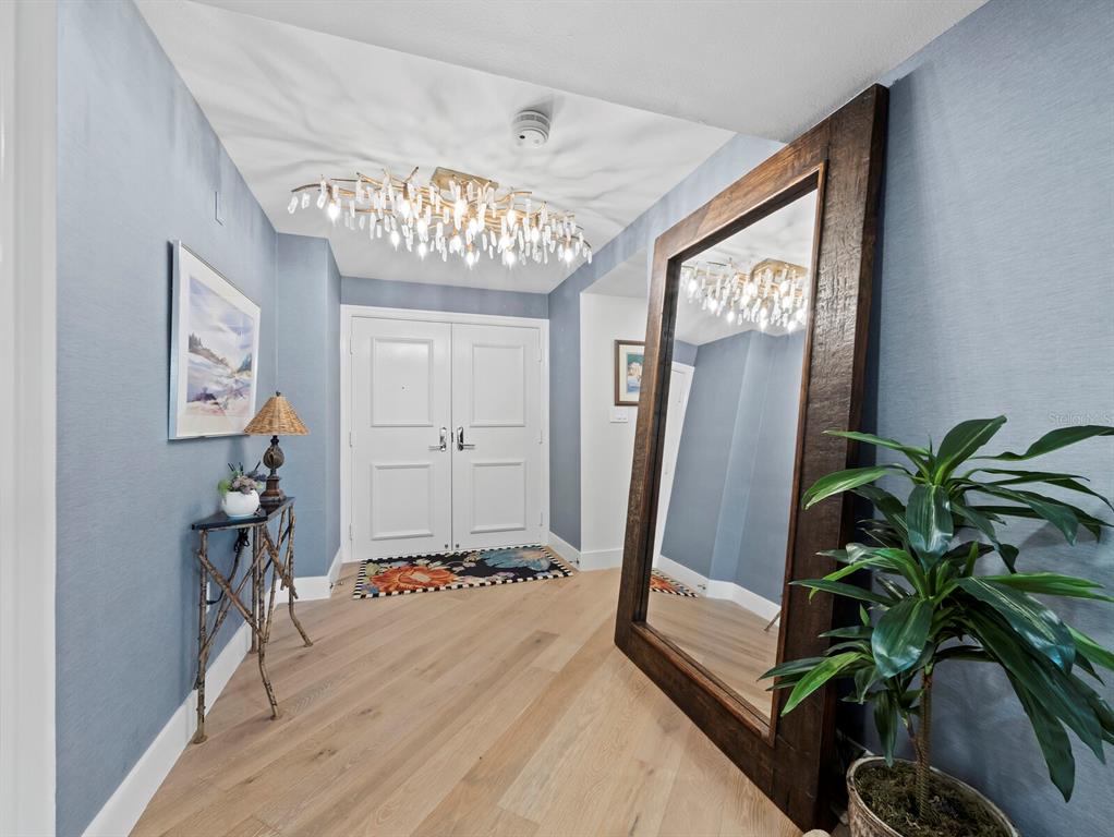 An entryway features light blue walls, a large floor mirror, and a crystal chandelier — 565 SANCTUARY DRIVE UNIT B106, LONGBOAT KEY, FL