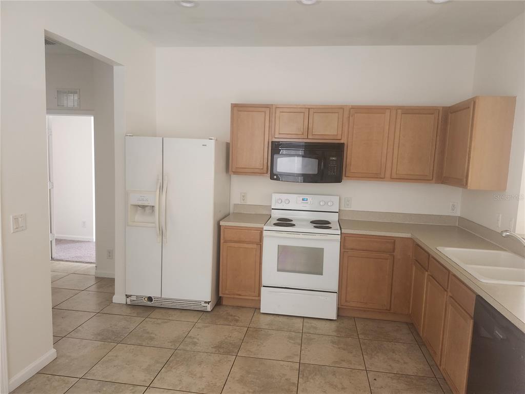 A kitchen with light wood cabinets, white appliances, and tan tile flooring — 14656 WAKE ROBIN DRIVE, BROOKSVILLE, FL