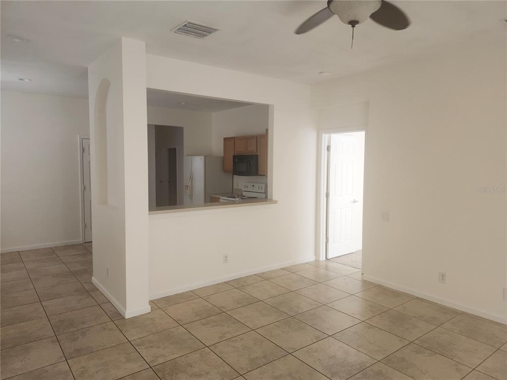 An interior view shows a tiled living area with a kitchen pass-through window — 14656 WAKE ROBIN DRIVE, BROOKSVILLE, FL