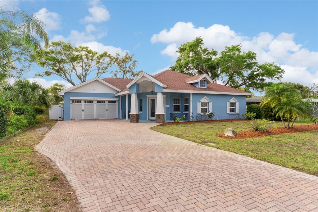 A blue single-story house with a brick paver driveway and a covered front entryway — 12080 143RD STREET, LARGO, FL