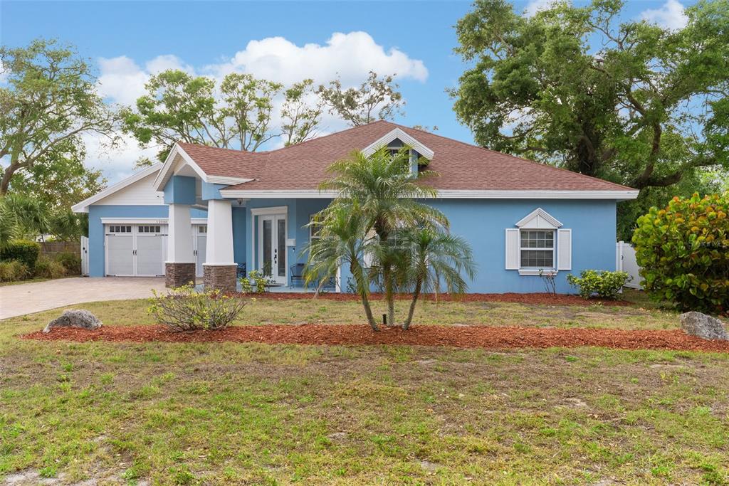 A blue single-story house with a brown roof, a front porch, and a palm tree — 12080 143RD STREET, LARGO, FL