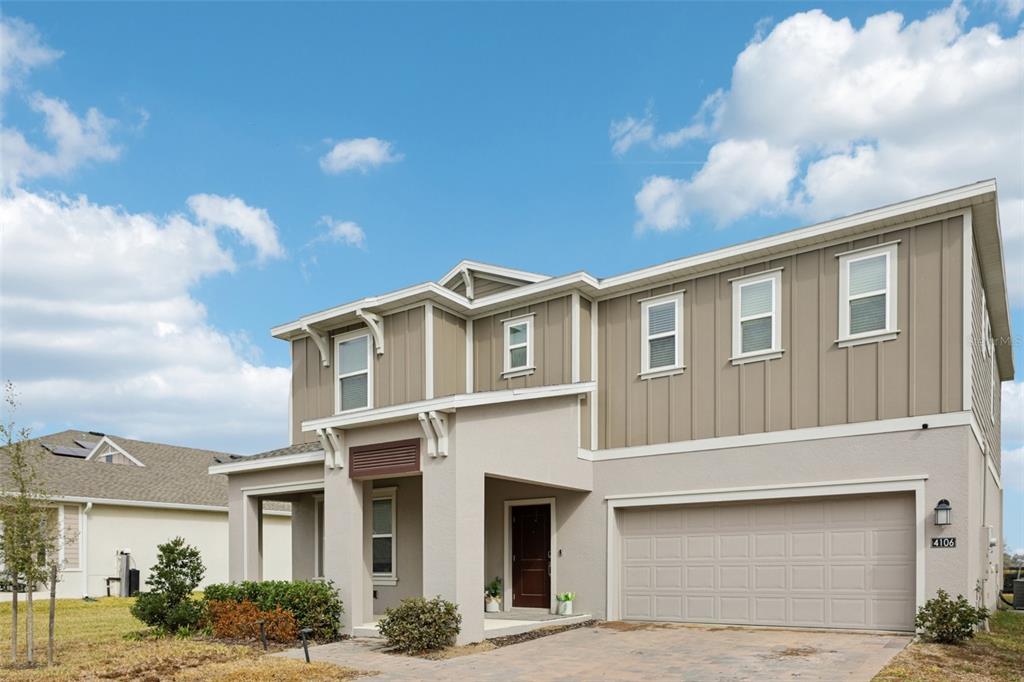 A two-story house with tan vertical siding, a stucco ground floor, and a two-car garage — 4106 CONJUNCTION WAY, APOPKA, FL