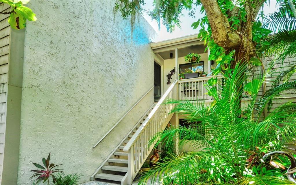 An exterior view shows a wooden staircase leading to a second-story balcony of a building — 1633 BOATHOUSE CIRCLE UNIT HA233, SARASOTA, FL