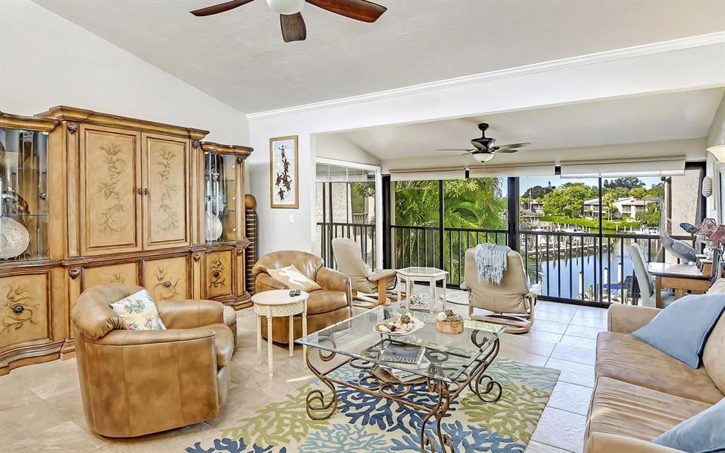 A living room with leather armchairs, a glass coffee table, and a view of water — 1633 BOATHOUSE CIRCLE UNIT HA233, SARASOTA, FL
