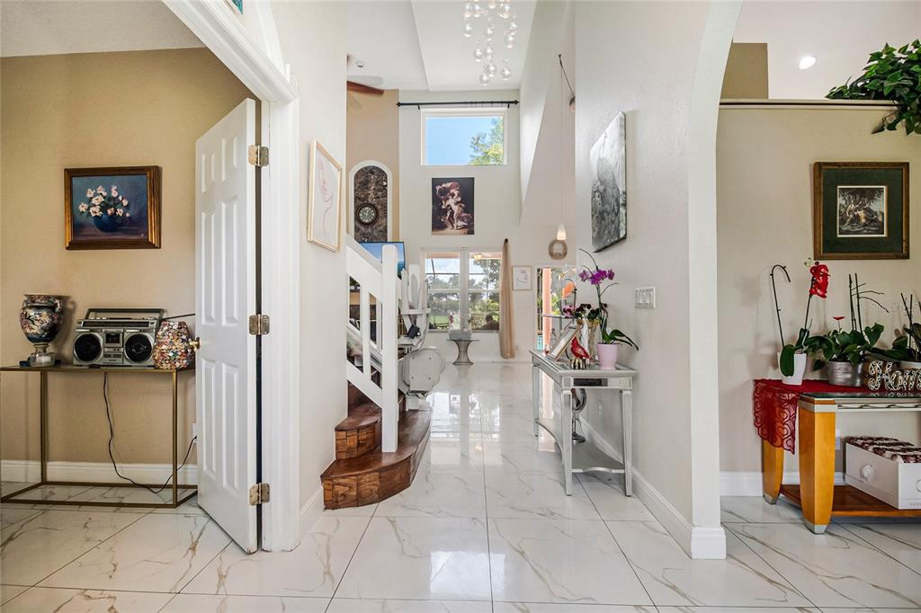 An entryway features white marble-look tile flooring, an arched opening, and bright red double doors — 13522 HERON CAY COURT, ORLANDO, FL
